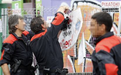 Miembros de la Ertzaintza procede a la retirada de carteles en las calles de Bilbao
