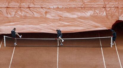 Unos trabajadores tapan la pista para protegerla de la lluvia durante la segunda jornada del Roland Garros en Pars (Francia).