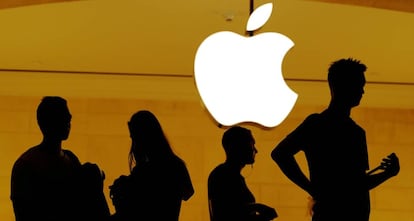 Clientes de una tienda de Apple ante un logo de la compañía.