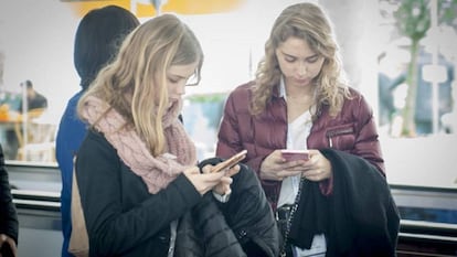 Dos jóvenes consultando sus teléfonos móviles.