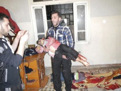 Imagen facilitada por la oposici&oacute;n siria de un hombre con el cad&aacute;ver de un ni&ntilde;o en brazos, asesinado en Karm al-Zeitoun, cerca de Homs.