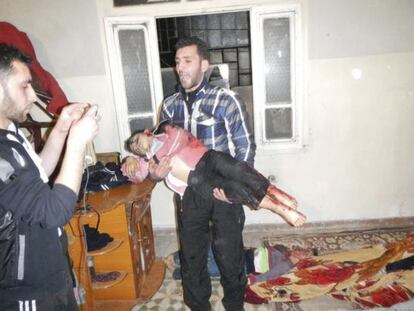 Imagen facilitada por la oposición siria de un hombre con el cadáver de un niño en brazos, asesinado en Karm al-Zeitoun, cerca de Homs.
