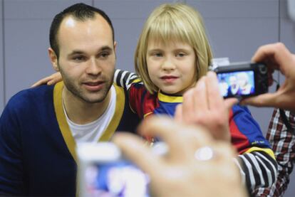 Iniesta se fotografía con una niña en su visita a un hospital de Barcelona.
