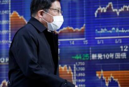 Un hombre con mascarilla, ante un panel del Nikkei, en Tokio.