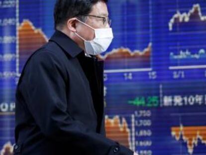 Un hombre con mascarilla, ante un panel del Nikkei, en Tokio.