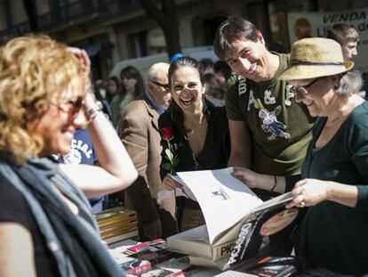 Unos ciudadanos posan sonriendo ante una parada de libros.