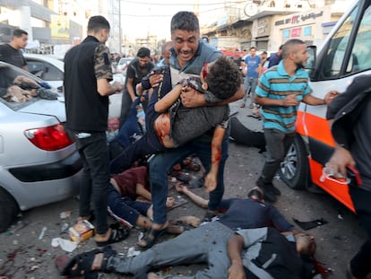 Un hombre, con víctimas a sus pies, cargaba el viernes con el cuerpo de un niño tras el ataque israelí a una ambulancia junto a la entrada del hospital Al Shifa de Gaza.