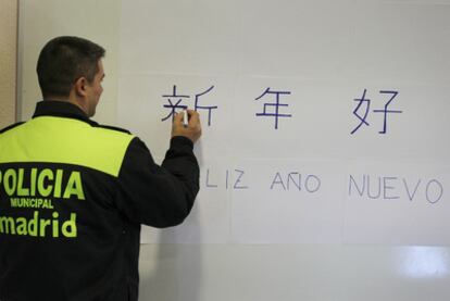 El policía municipal Manuel García Vargas felicita en chino el año nuevo en una pizarra de la sede de Usera.