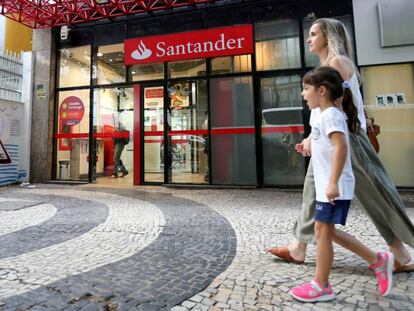 Una mujer y una ni&ntilde;a pasean frente a una sucursal del Banco Santander.