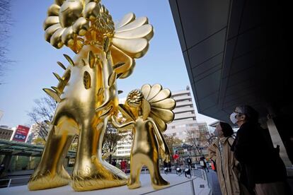 Los transeúntes observan 'Flower Parent and Child' del artista contemporáneo japonés Takashi Murakami que se muestra en Roppongi Hills 66 Plaza en Tokio (Japón). Con un peso de más de 11 toneladas, la escultura dorada de 10 metros de altura es una de las obras de arte más grandes de Murakami.