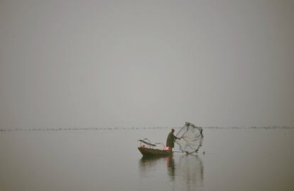 Un pescador de Cachemira lanza su red en mitad de la niebla densa en el lago Dal en Srinagar.