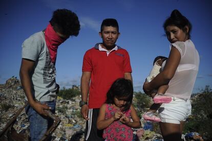 La familia Reyes está compuesta por seis miembros. Trabajan reciclando basura sin utensilios como guantes o botas. “Hace seis meses, la plaga llegó al pueblo. Empezó a extenderse, no sabíamos qué hacer, decían que era la nueva cepa, la amazónica. Fueron cayendo miembros de cada familia, decenas de muertos. Nadie vino a socorrernos, fue horroroso”, describe el padre de familia. “Encima, no despejaron el único acceso que hay desde el botadero —vertedero— al pueblo. Eso debería hacerlo la Municipalidad con las orugas —máquinas que arrastran los desechos—. Nos encerraron. Nos dejaron morir lentamente”..