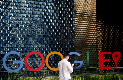 Un hombre mira su móvil mientras camina frente al logo de Google, en Singapur.