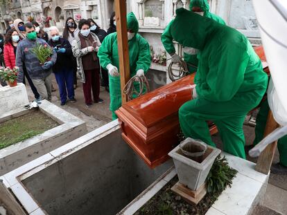 Trabajadores del cementerio de Colina, en las afueras de Santiago, manipulan el ataúd de un hombre de 68 años que murió víctima de la covid-19.