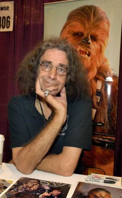 Peter Mayhew, e um cartaz com a imagem de seu personagem famoso, Chewbacca, de 'Star Wars'.