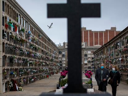 Una mujer y su hermano caminan por el cementerio de Poble Nou tras asistir al entierro de su madre, este sábado en Barcelona.