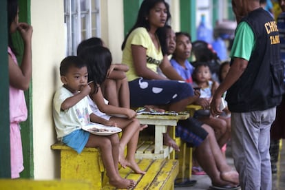 Un niño come junto a otros evacuados de un centro de acogida temporal en la ciudad de Tuguegarao, Filipinas.