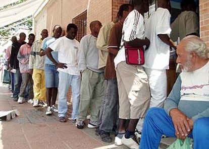 Inmigrantes subsaharianos hacen cola para recibir su ración diaria de comida en el comedor ceutí de la Cruz Blanca.