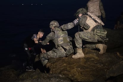 Dos soldados del Ejército español ayudan a salir del agua a un joven marroquí que cruzó a nado la frontera la noche del 18 de mayo.