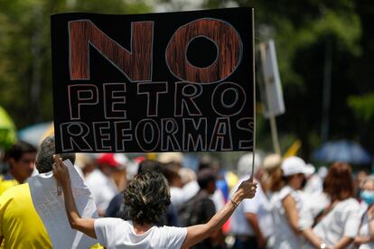 Una mujer sostiene un cartel con un mensaje en contra de las reformas de Gustavo Petro, en Cali. 