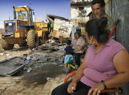 Una familia del asentamiento de gitanos, ayer, mientras una excavadora del Ayuntamiento de Valencia derribaba las chabolas.