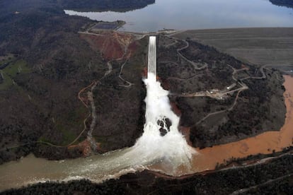 A água se evade com capacidade máxima pelo deságue da represa de Oroville, na segunda-feira. À esquerda, o dique de contenção emergencial danificado.