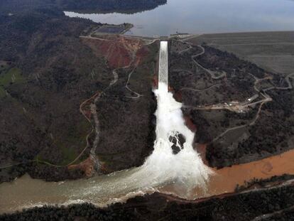 A água se evade com capacidade máxima pelo deságue da represa de Oroville, na segunda-feira. À esquerda, o dique de contenção emergencial danificado.