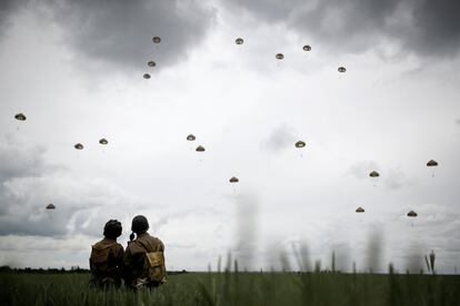 Dos soldados observan cómo varios paracaidistas saltan de aviones sobre Sannverville (Francia) para conmemorar el 75º aniversario del Día D.