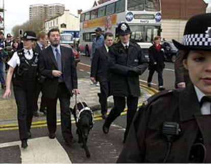 El ministro del Interior, David Blunkett, es ayudado por una policía a cruzar una calle del centro de Bristol.