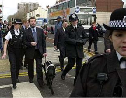 El ministro del Interior, David Blunkett, es ayudado por una policía a cruzar una calle del centro de Bristol.