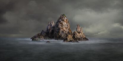 'At the Edge of Despair' retrata la icónica Camel Rock (Australia) bajo los primeros rayos de sol que pueden vislumbrarse en un cielo encapotado que resaltan su forma escarpada y prehistórica en la que rompen las olas. La fotografía ofrece al espectador un aura mística y de fantasía de este paraje natural en Nueva Gales del Sur.