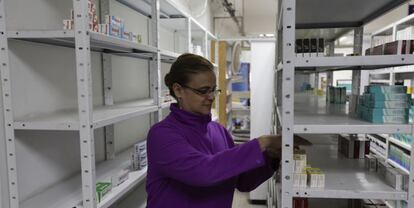 Una empleada de una farmacia toma medicinas de una estanter&iacute;a en Caracas.