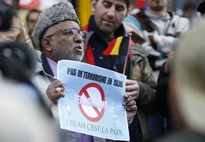 Un hombre sostiene una pancarta entre la multitud en uno de los monumentos a las víctimas de los recientes ataques de Bruselas.