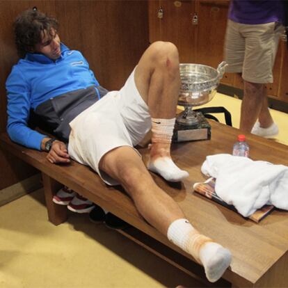 Rafael Nadal, exhausto tras la final, descansa en su vestuario junto al trofeo de campeón.