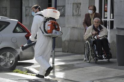 An elderly couple observes a man disinfecting the streets of Vitoria in Spain’s Basque Country on Monday.