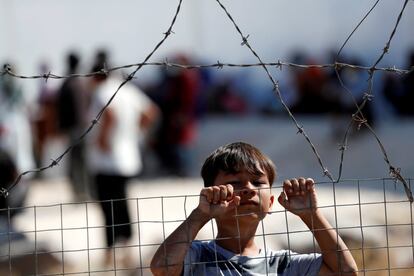 Un niño observa a través de una valla en el nuevo campamento temporal para migrantes y refugiados, en la isla de Lesbos (Grecia).