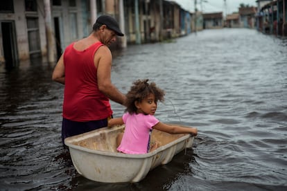 Jesús Hernández con su nieta Angelina en una calle inundada tras el paso del huracán Helene en Batabano, Cuba, en septiembre del 2024.