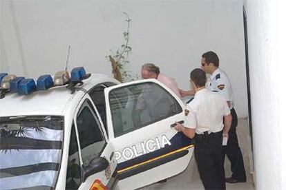 Dos agentes introducen en el coche policial al empresario Carlos Sánchez.