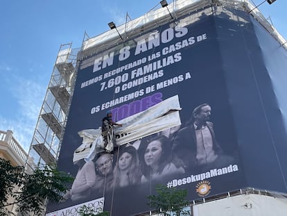 Un operario retira los carteles pegados por el Movimiento por la Vivienda de Madrid sobre la lona de Desokupa en la calle de Atocha. 