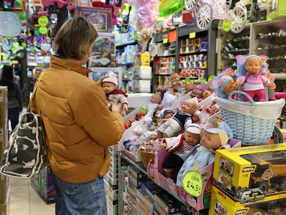 Una mujer sostiene un muñeco en una tienda de juguetes la víspera del día de Reyes de 2023.