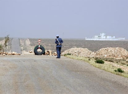 Un gendarme marroquí camina, cerca de Ain Beni Mathar, en medio de una carretera cortada que en su día condujo a Argelia. A su derecha el edificio blanco es un puesto de vigilancia del Ejército Nacional Popular argelino.