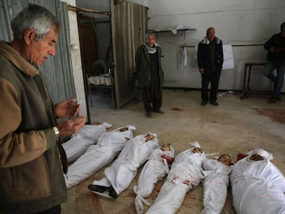 Un hombre reza frente a los cadáveres de varios niños víctimas del último bombardeo del régimen sirio.