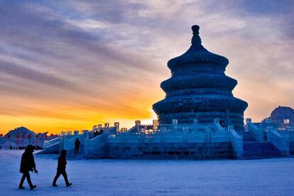 Una pareja de turistas camina frente a un templo, en el Gran Mundo de Hielo y Nieve de Changchun (China).