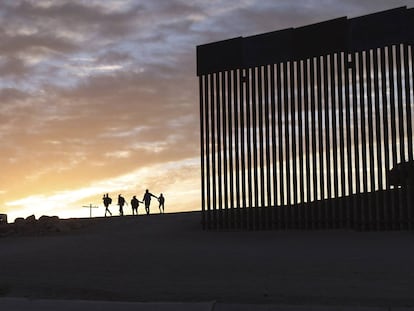 Un par de familias migrantes provenientes de Brasil pasan por un hueco del muro fronterizo para alcanzar Estados Unidos tras cruzar México, en Yuma, Arizona, EE UU.