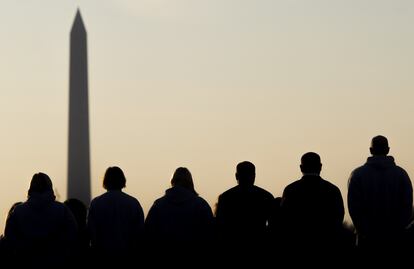 Un grupo de hombres y mujeres observa el obelisco de Washington.