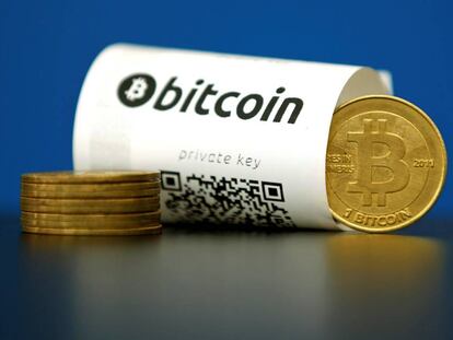 Un papel de bitcoin (virtual currency) con su código QR y una moneda.