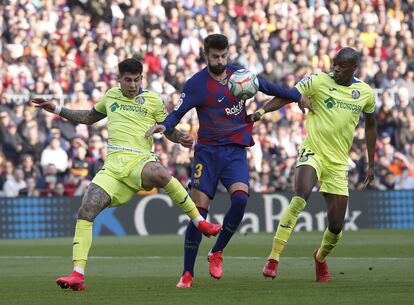 Gerard Piqué intenta zafarse de los jugadores del Getafe Mathias Olivera y Allan Nyom.