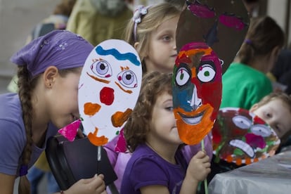 Ni&ntilde;os ense&ntilde;an las m&aacute;scaras que han fabricado en el taller Cara a Cara, en el paseo de Picasso.