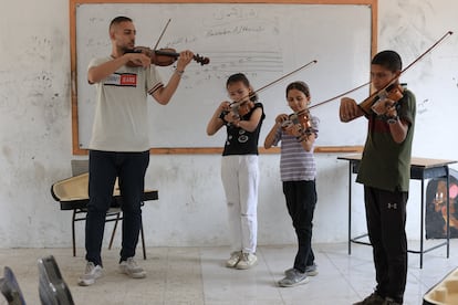 "Cuando toco, siento que estoy curando heridas con el violín", expresa Hamada al Kharoubi, de 25 años. En la fotografía,  Al Kharoubi toca el instrumento junto a tres niños en el Gaza College, el 9 de agosto de 2025.