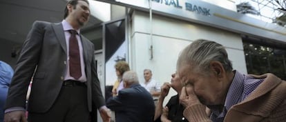 Un director de una sucursal del Banco Nacional de Grecia en Tesalónica explica la situación a un grupo de pensionistas que espera fuera de la oficina.